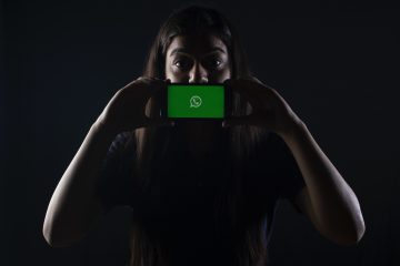 woman holding black smartphone at Whatsapp logo